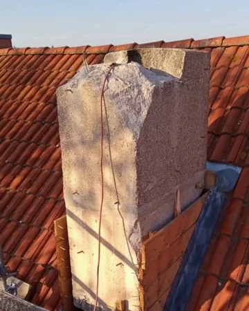 Alter Schornstein auf Ziegeldach während des Rückbaus – Beton freigelegt und Abbrucharbeiten vorbereitet